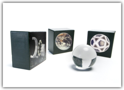 The image shows a glass marble and three black cubes, in which the marble is reflected: once as part of a ball bearing, once as a globe, and once as a soccer ball. When you hover over the image, a short description appears: Interpret - Improve the consideration of your concepts through relevant information, proactive discussions of target group expectations, and the understanding of all participants.<br />©memephoto