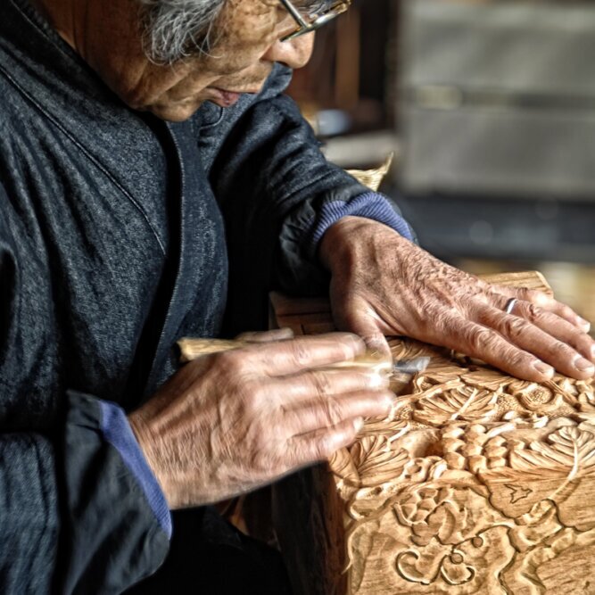 The photo shows a detail of a Japanese woodcarver at work.<br />©memephoto