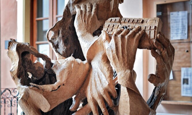 The photo shows a wooden sculpture with four twisted hands acting, such as typing.<br />©memephoto