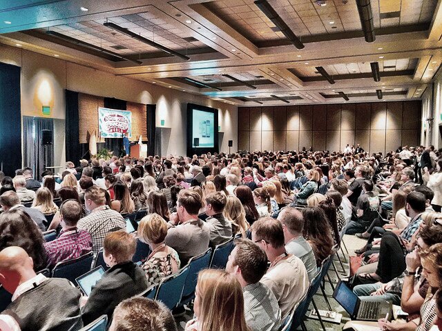 The photo shows a hall with many people watching a presentation from the front, taken from a diagonal rear angle.<br />©Stocknation